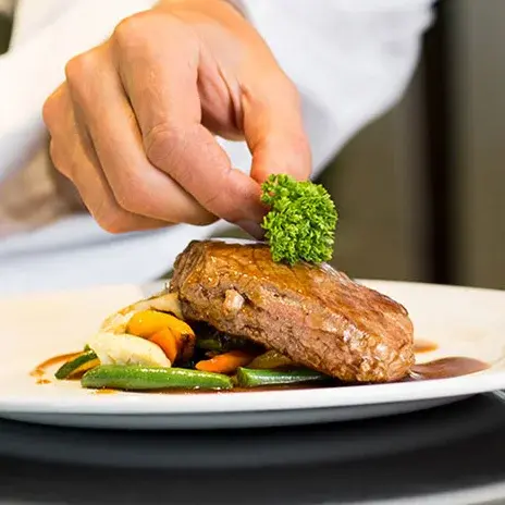 El Dorado Estates Chef Created Meals, chef garnishing a plate.